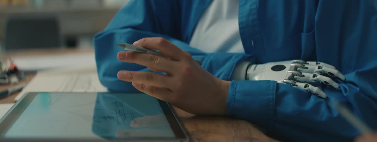 Woman with a prosthetic hand references a tablet while holding a discussion in an office