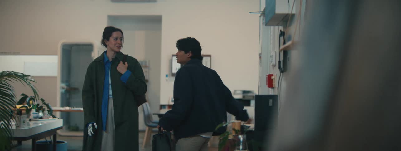 Man and woman walking out of a door and talking in the hallway