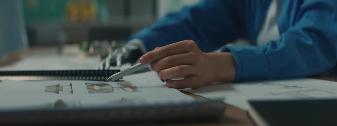 A woman and man sit in a school and work together with documents filled with diagrams