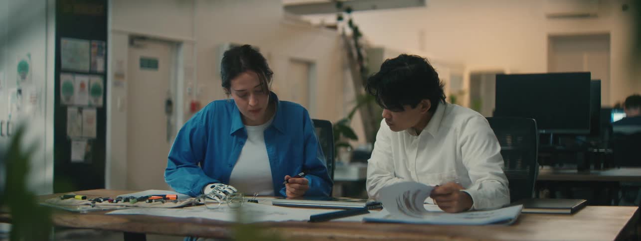 Two students sit in a school and work together at a table