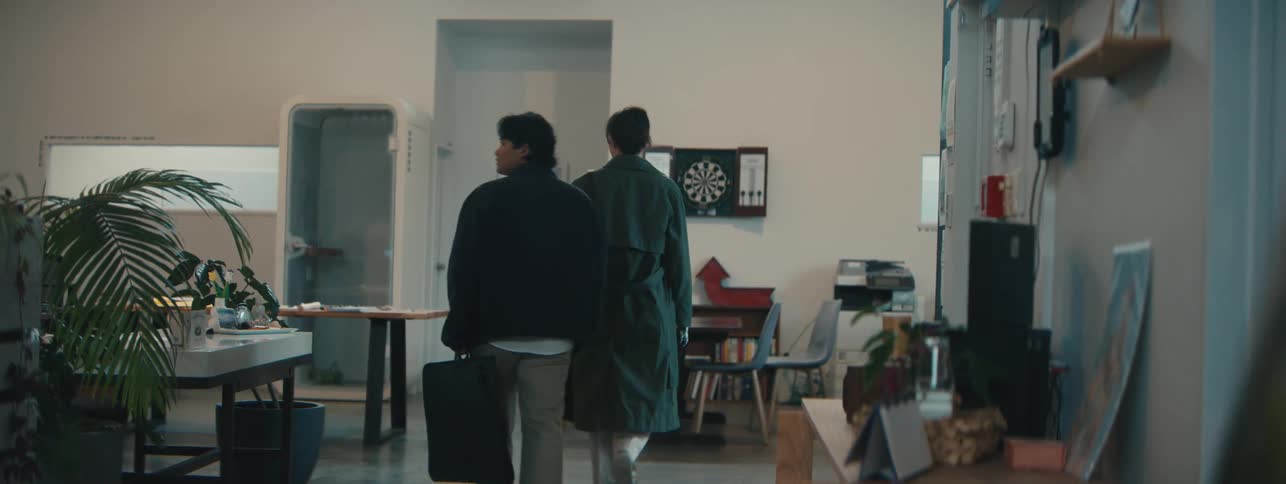 Coworkers arrive at the office and walk to a table for a discussion