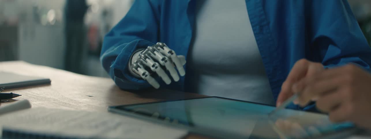 Woman with a prosthetic limb gestures at a tablet while collaborating in the office
