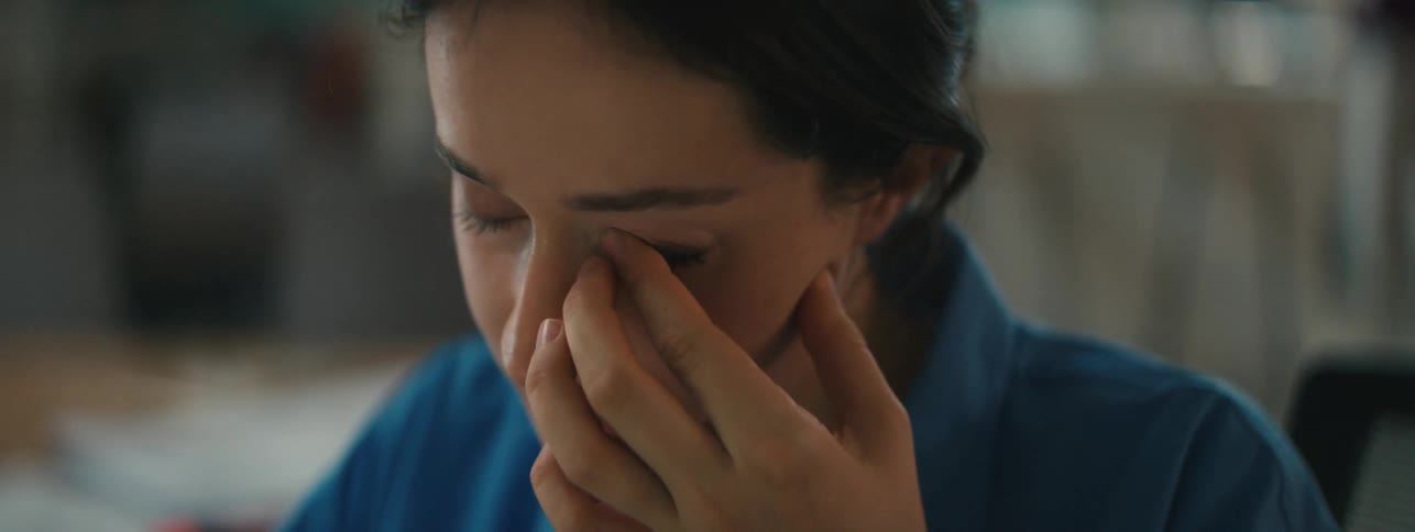 A contemplative and sad woman touches her face and rubs her eye