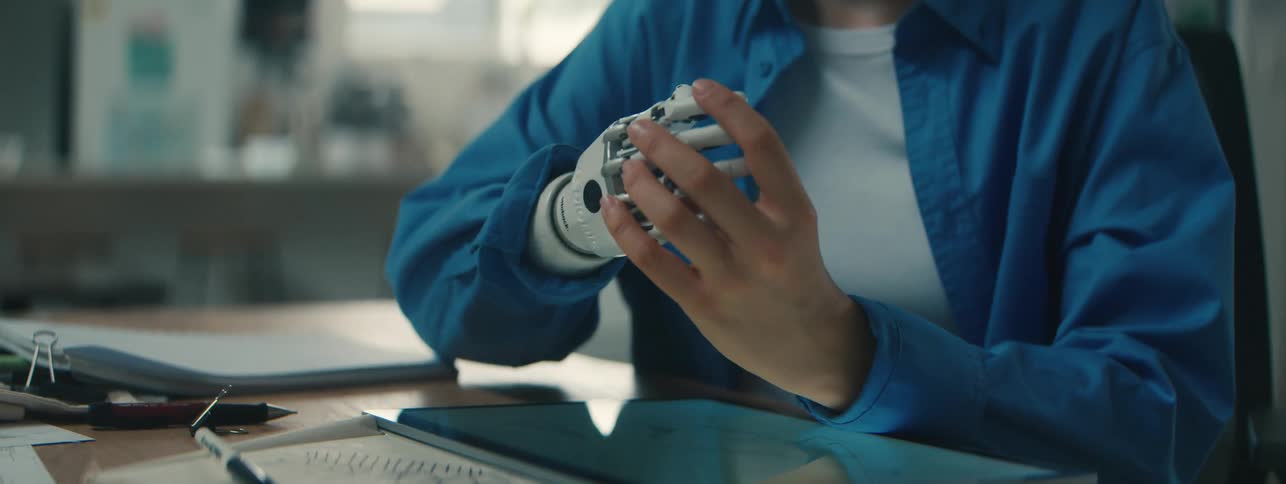 A woman waves her prosthetic hand as she talks