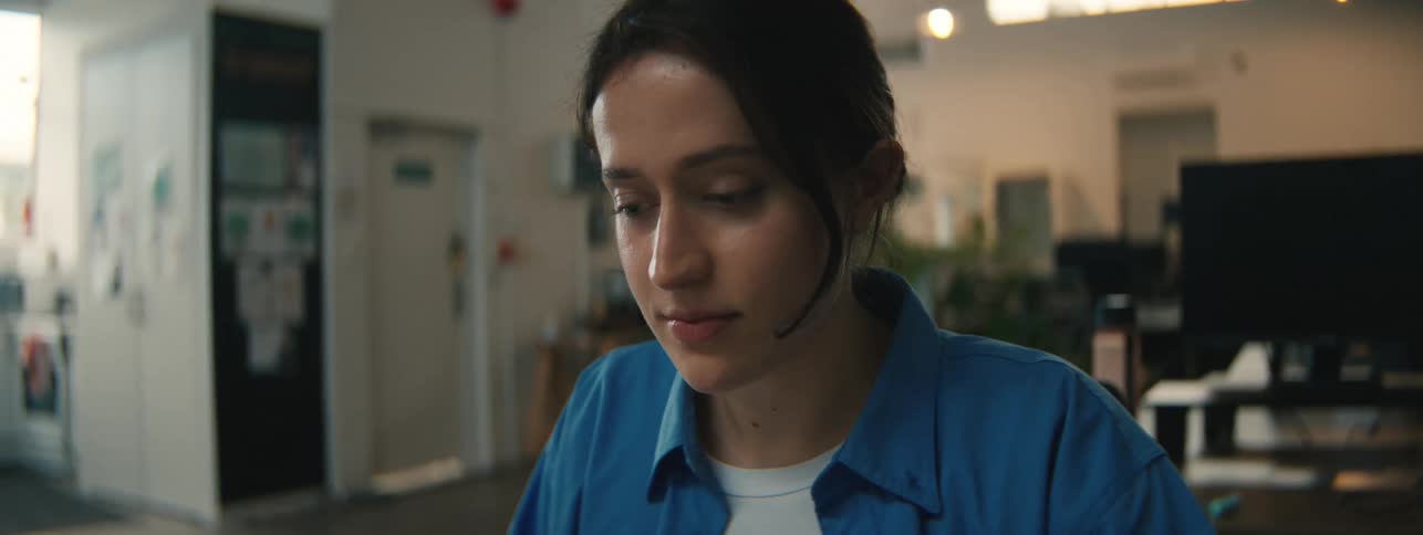 Close up of the face of a woman wearing a blue top sitting on a room