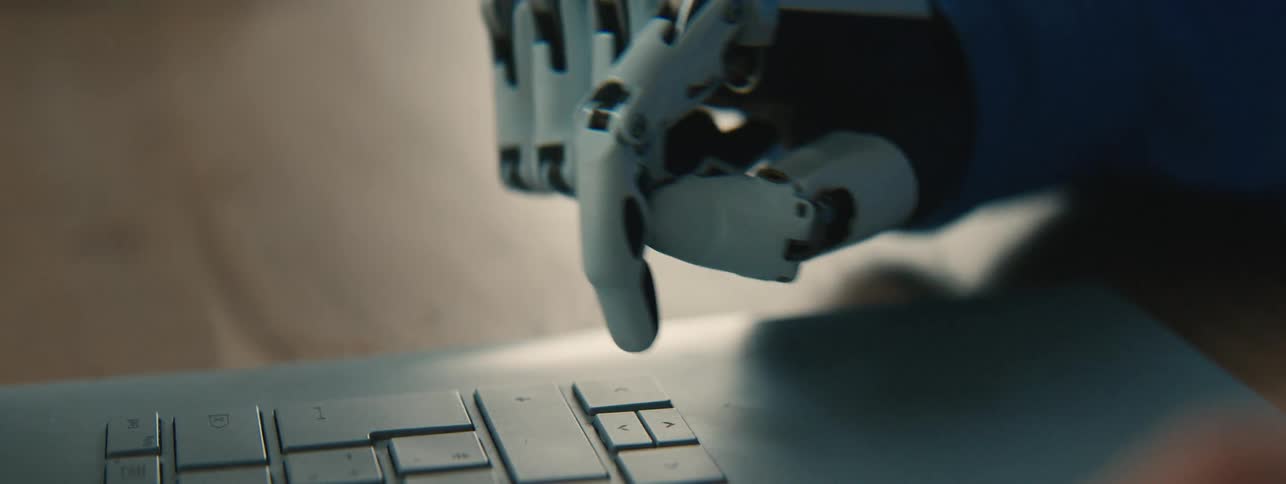 A person wearing a prosthetic hand taps a key on a laptop