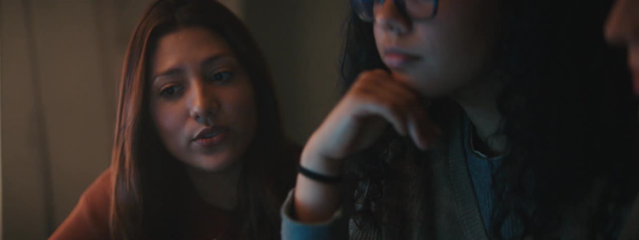 Portrait of three women focused in front of a screen in a lowlight environment