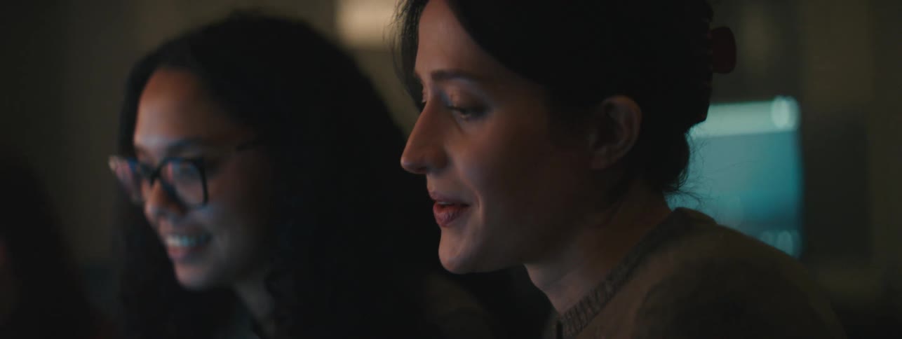 Trio of women sitting in a lowlit room talking