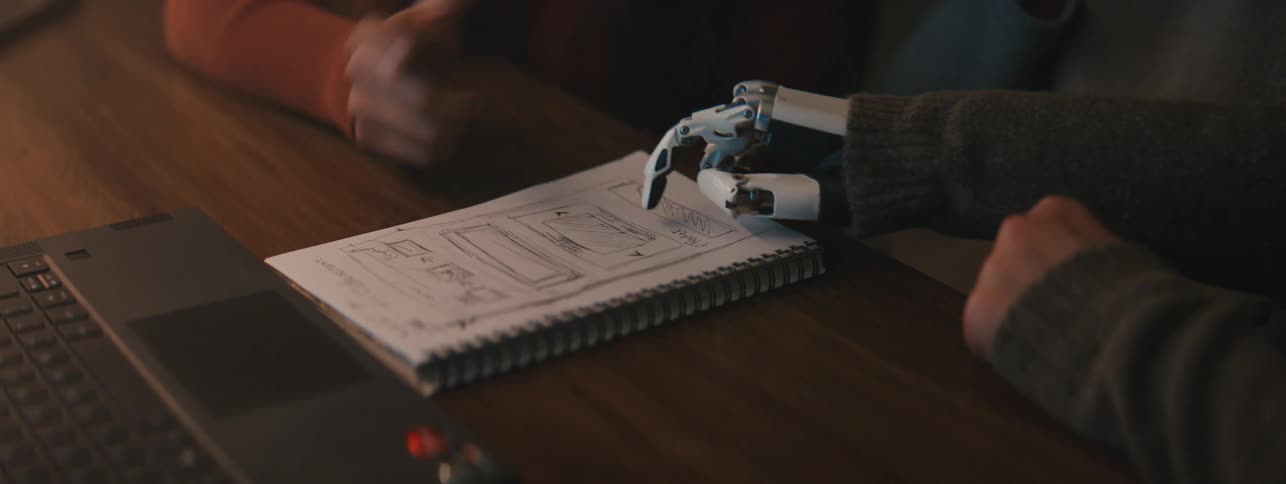 Robotic hand on top of a book with a human hand next to it