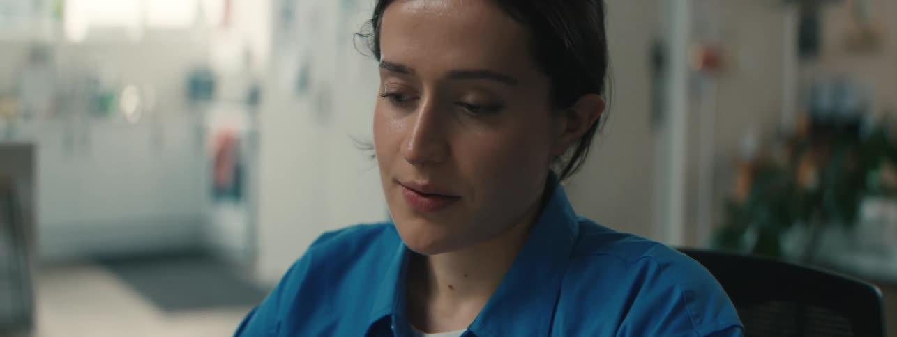 A contemplative woman tilts her head and smiles then leans forward