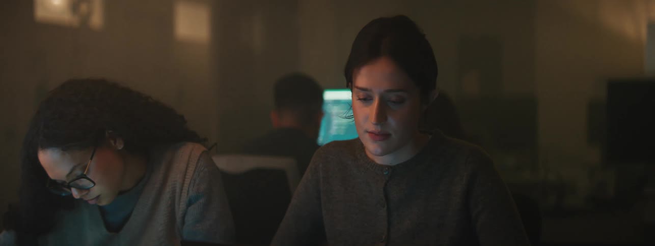 An indian student talks to two other female students in a computer lab