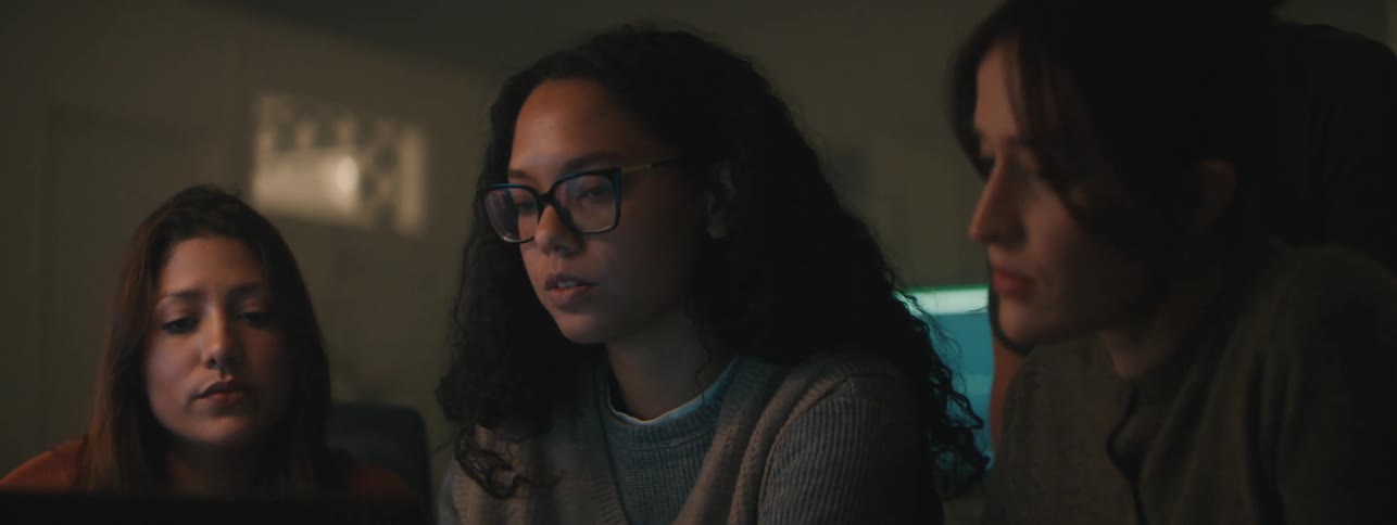 Three women and a man stare at something and have a discussion