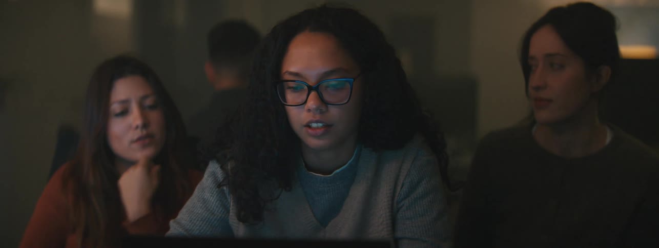 Three women sitting talking in front of a laptop