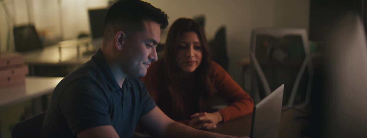 Man typing on a laptop next to a woman