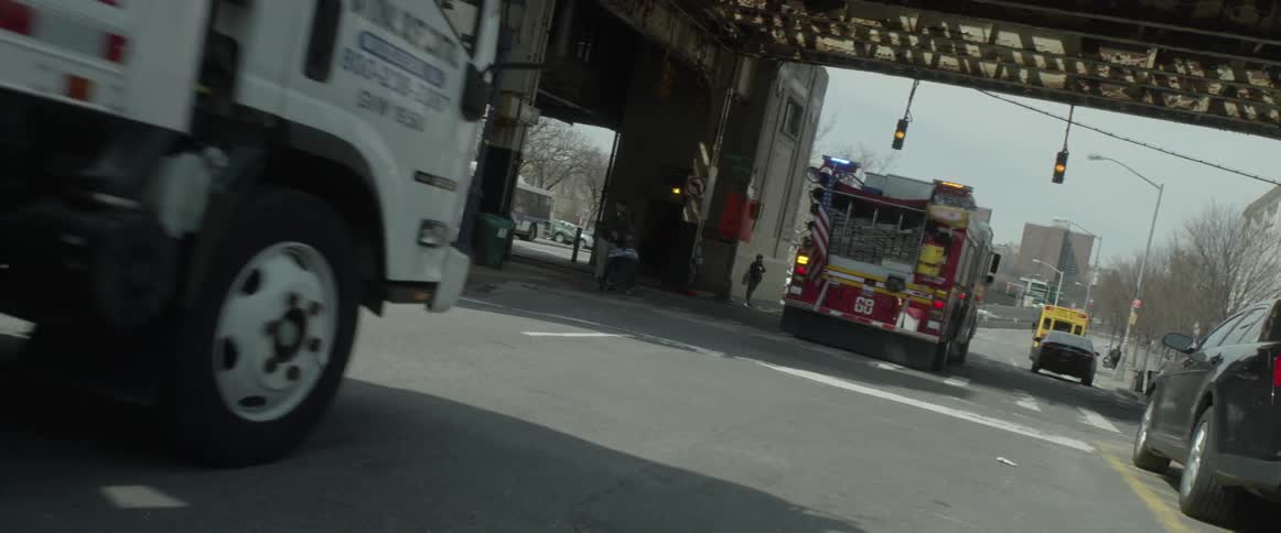 Two large trucks drive down a city street