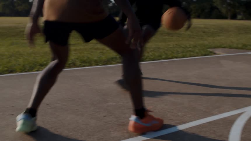 Two young men playing basketball one on one in a park