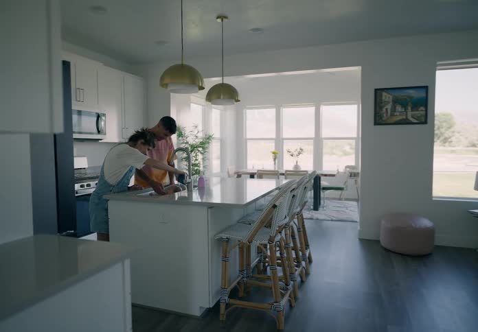 A young couple bathing a baby in the kitchen sink at home