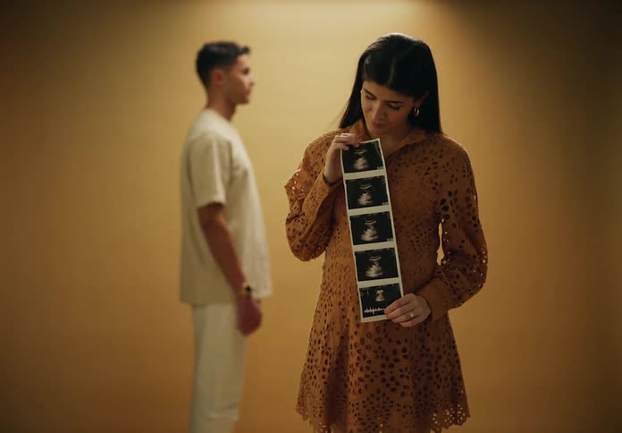 Man in the background and a woman in the foreground showing an ultrasound