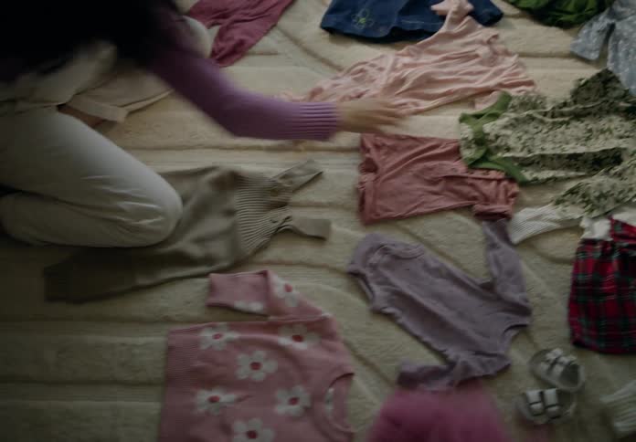 Woman goes through baby clothes on a rug