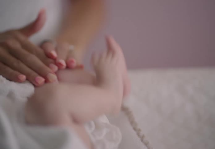 An adult female hand caressing a babys legs