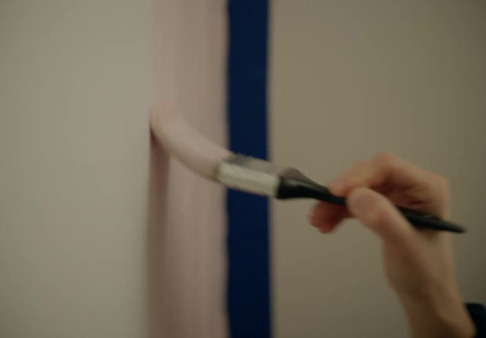 Smiling woman wearing a sweatshirt paints the wall
