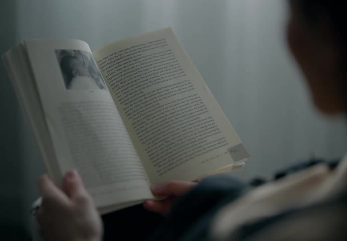 Closeup of a person sitting on a room reading a book