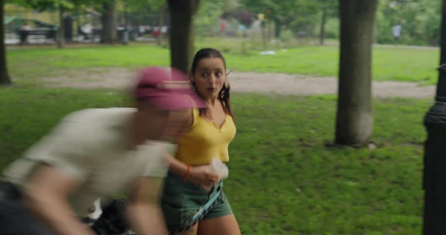 Woman walking in the park with her dogs and falling to the ground after a man passes by on a bicycle