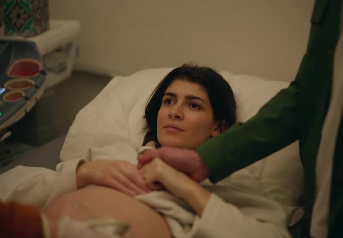 A woman lying on a medical examination bed with her abdomen exposed undergoing an ultrasound procedure