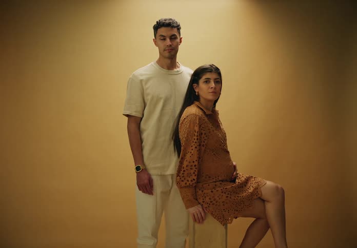 Pregnant woman sitting next to a man posing for a photo