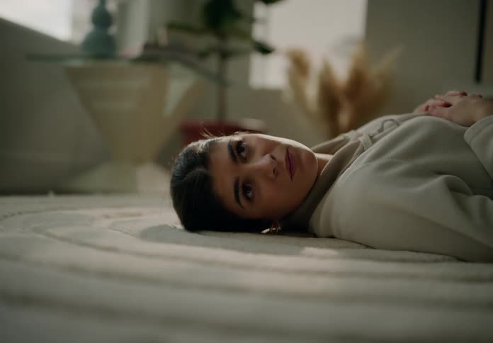 A young woman is lying on a carpet on the floor and is moving her head