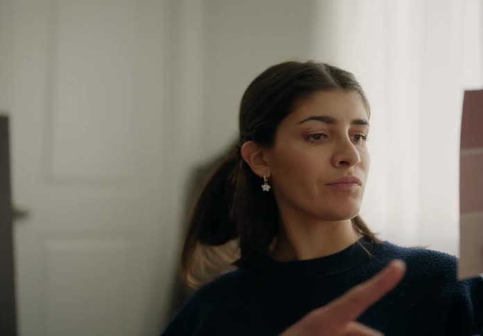A woman holding up a color swatch inside a room comparing paint options