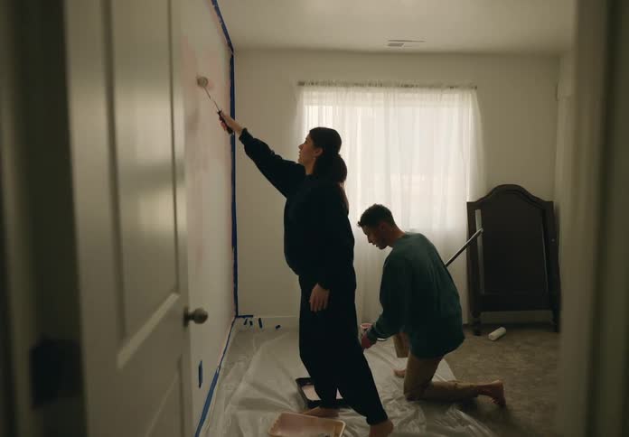 Couple in a room painting the wall