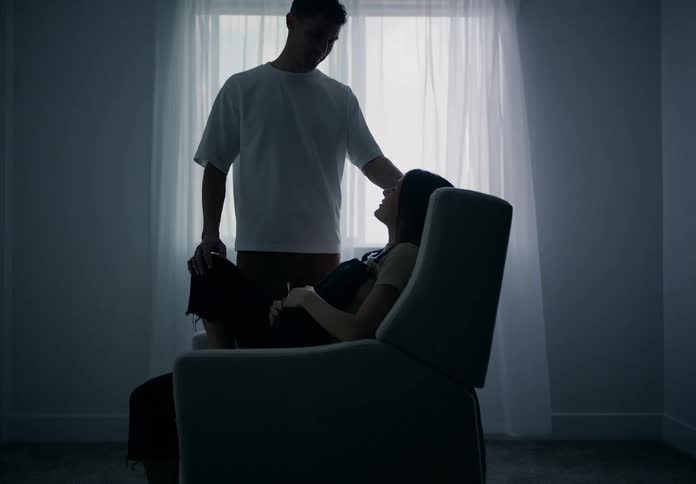 Man kisses pregnant woman on the head while she rocks in a chair