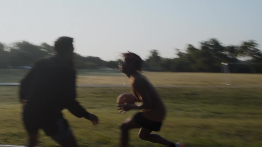 Two young men playing basketball one on one in a park