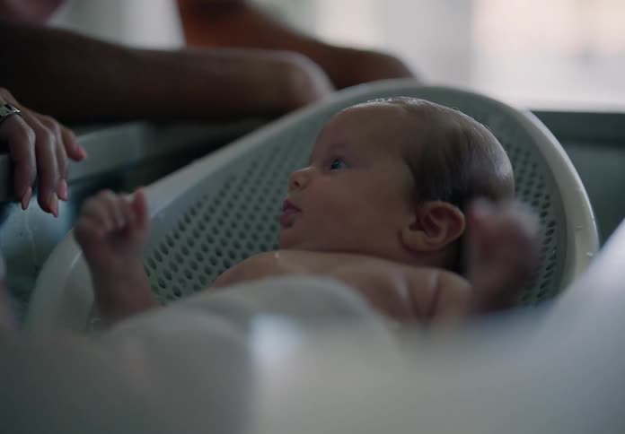 Father and mother bathing little baby in a sink