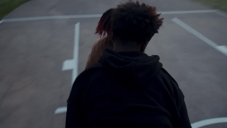 Two teenagers playing basketball on a court in the late afternoon
