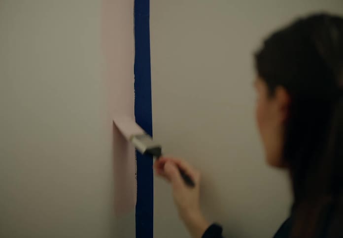 A woman is painting a wall