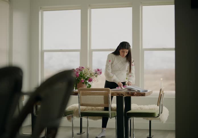 Woman standing next to table picking flowers from a vase