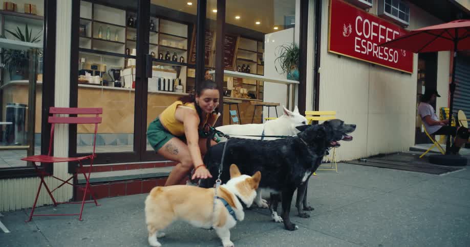 Woman holding a glass of juice and with her four dogs next to a coffee shop
