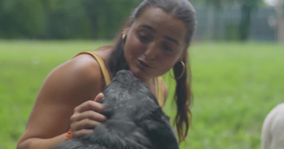 Woman on the grass petting a dog
