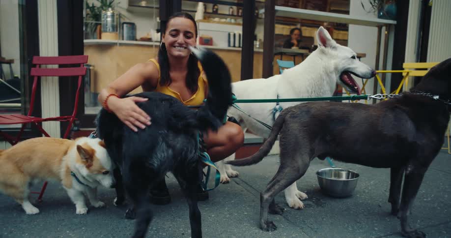 Happy woman crouching with her four dogs on the sidewalk of an establishment