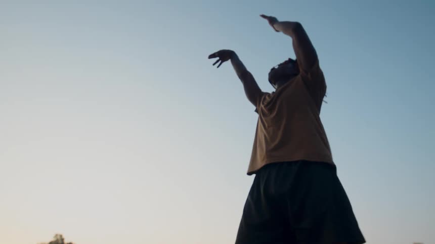 Boy jumping and shooting a basketball on an outdoor court