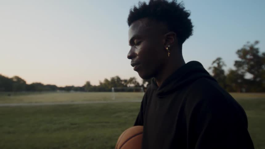 Man holding a basketball on a court taking a deep breath