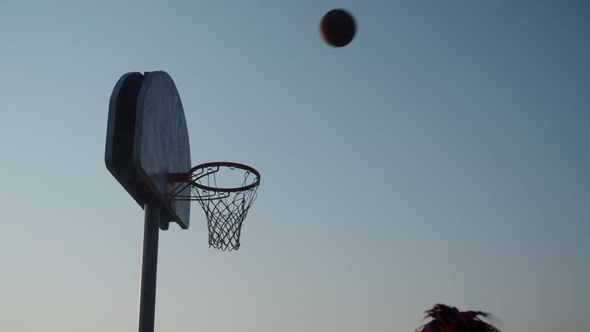 A basketball bounces off a hoop during the evening