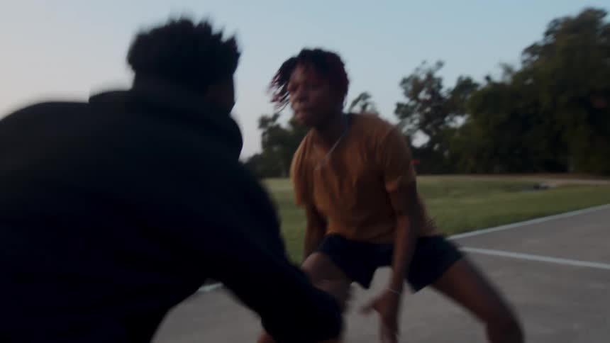 Two young teenagers playing basketball on an outdoor court