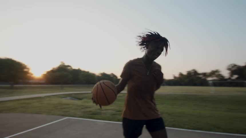 Young man on an open air court playing basketball