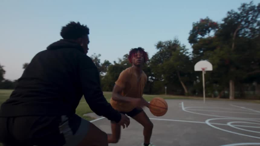 Two men are playing basketball on a concrete court and one of them throws the ball and is happy