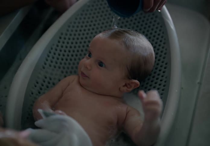 Hands bathing a baby in the kitchen sink
