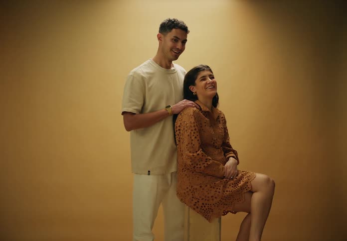 Man standing with hands on the shoulder of his pregnant wife posing in a studio