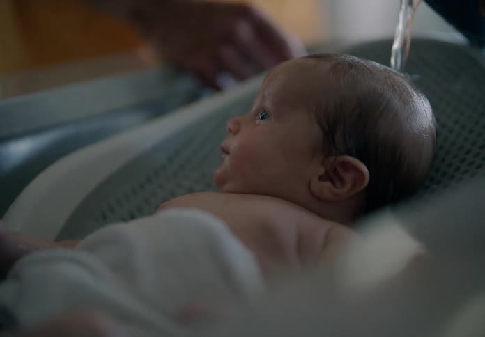 Close up of a couple giving a newborn baby a bath at home